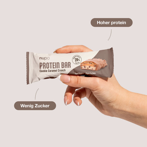 Hand hält Nupo Proteinriegel Probierpaket – 12 Riegel mit Cookie Caramel Crunch, hoher Proteingehalt.