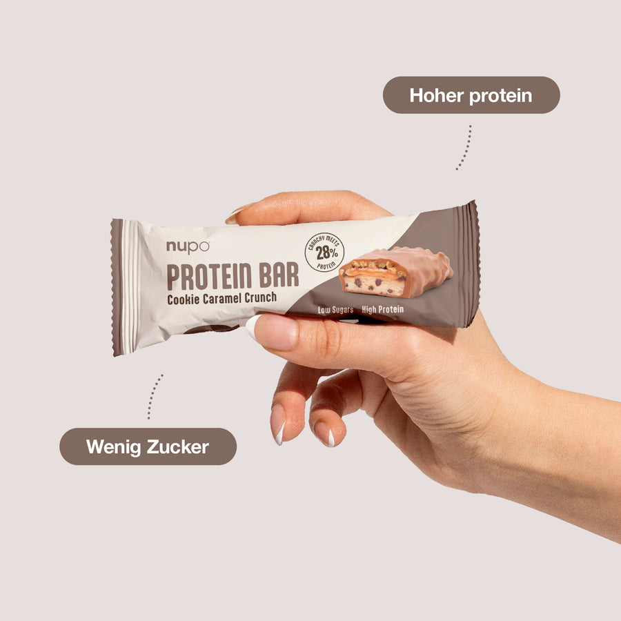 Hand hält Nupo Proteinriegel Probierpaket – 12 Riegel mit Cookie Caramel Crunch, hoher Proteingehalt.