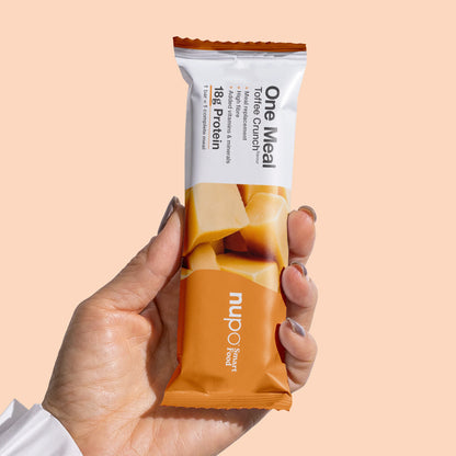 Nupo One Meal Bar Toffee Crunch Riegel in der Hand – praktischer Mahlzeitersatz für unterwegs
